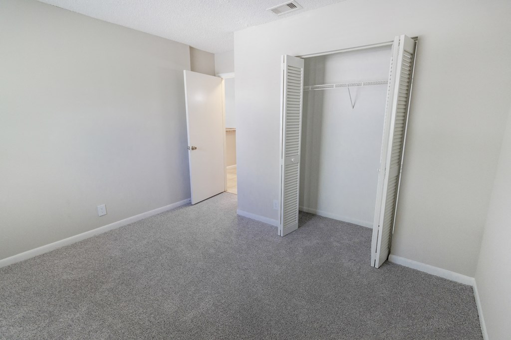 A room with a grey carpet and a white door.